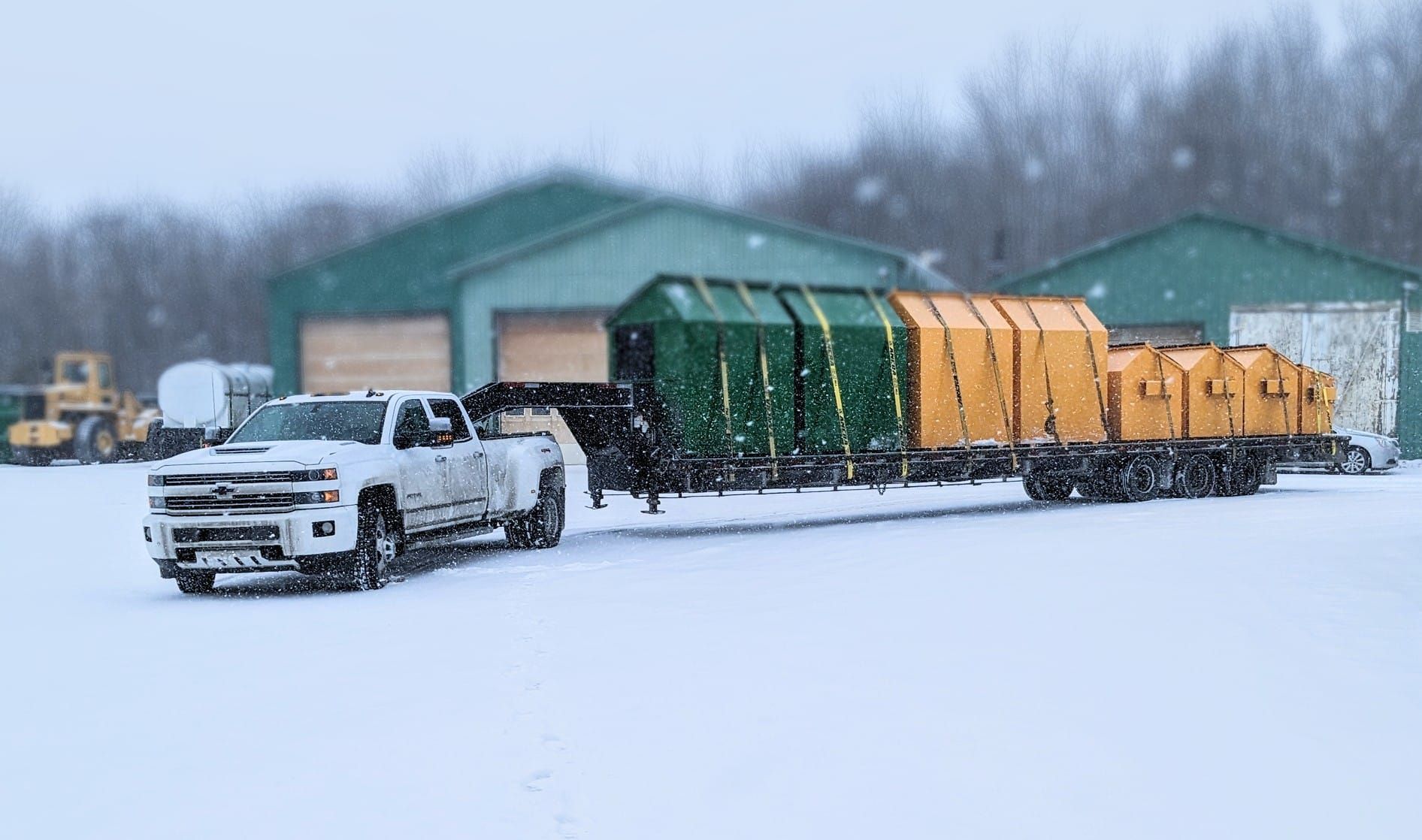 Un camion blanc remorque un train dans la neige.