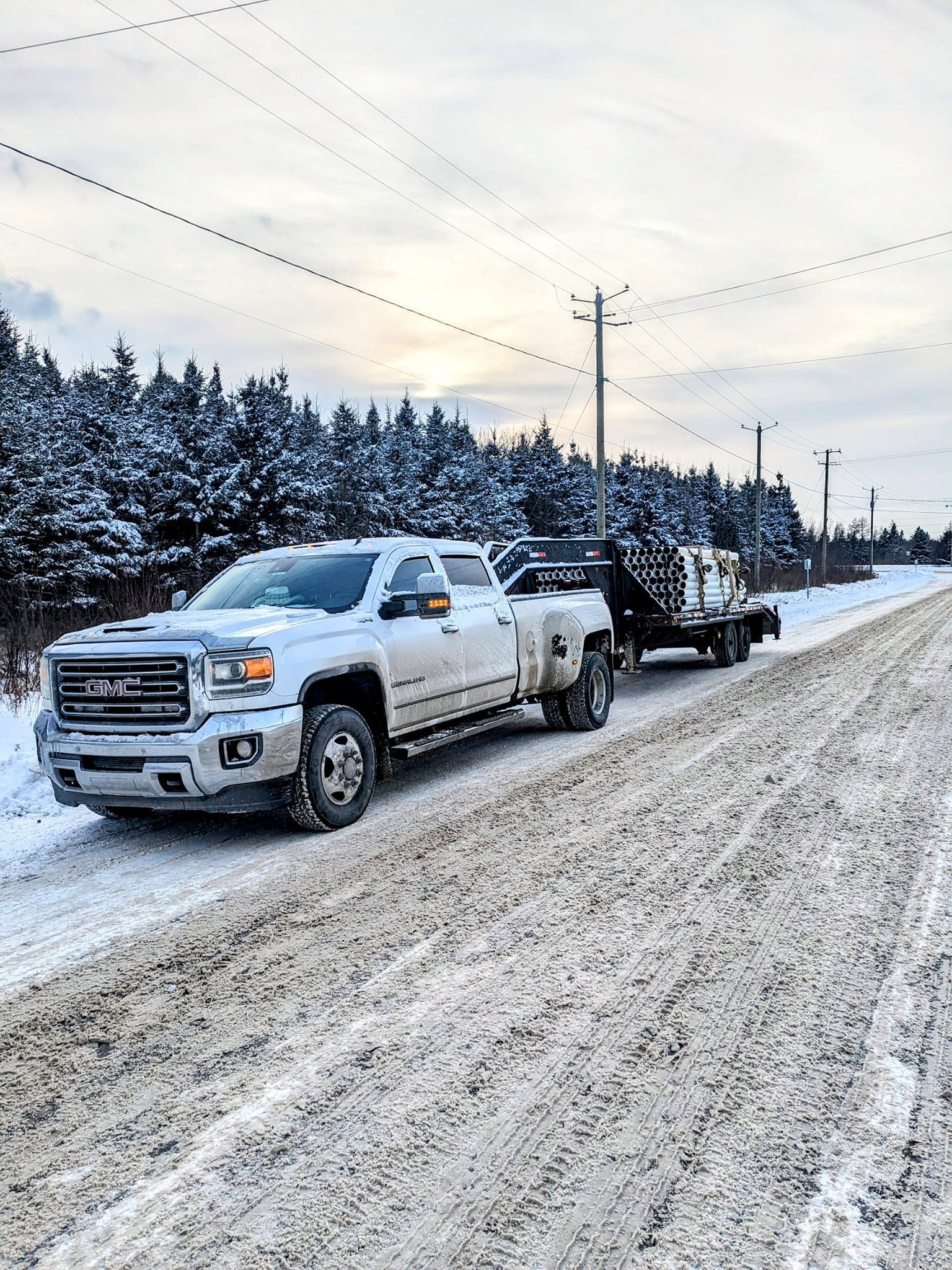 Un camion blanc tire une remorque sur une route enneigée.