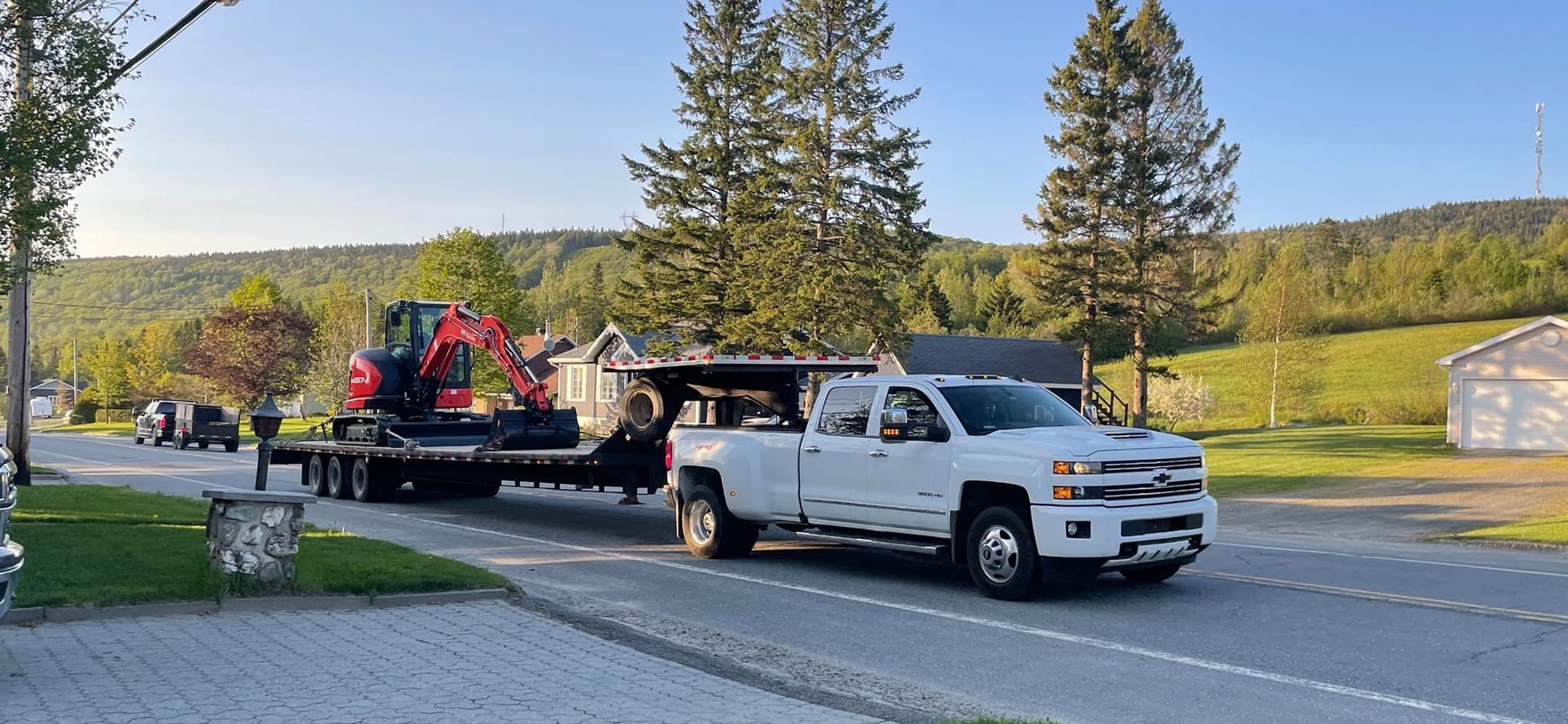 Un camion blanc tracte une remorque avec un tracteur dessus.