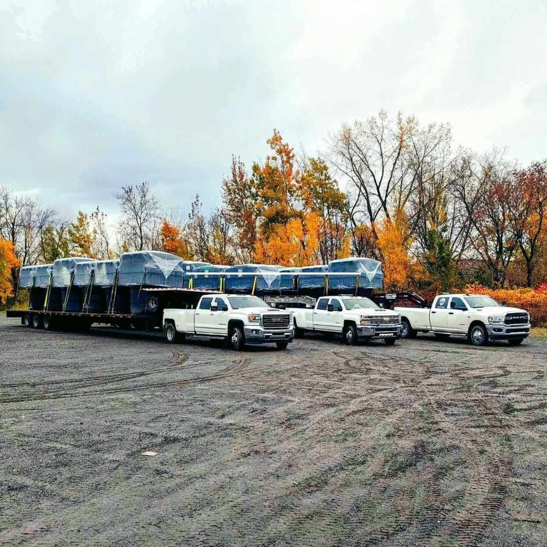 Une rangée de camions est garée sur un terrain en terre.
