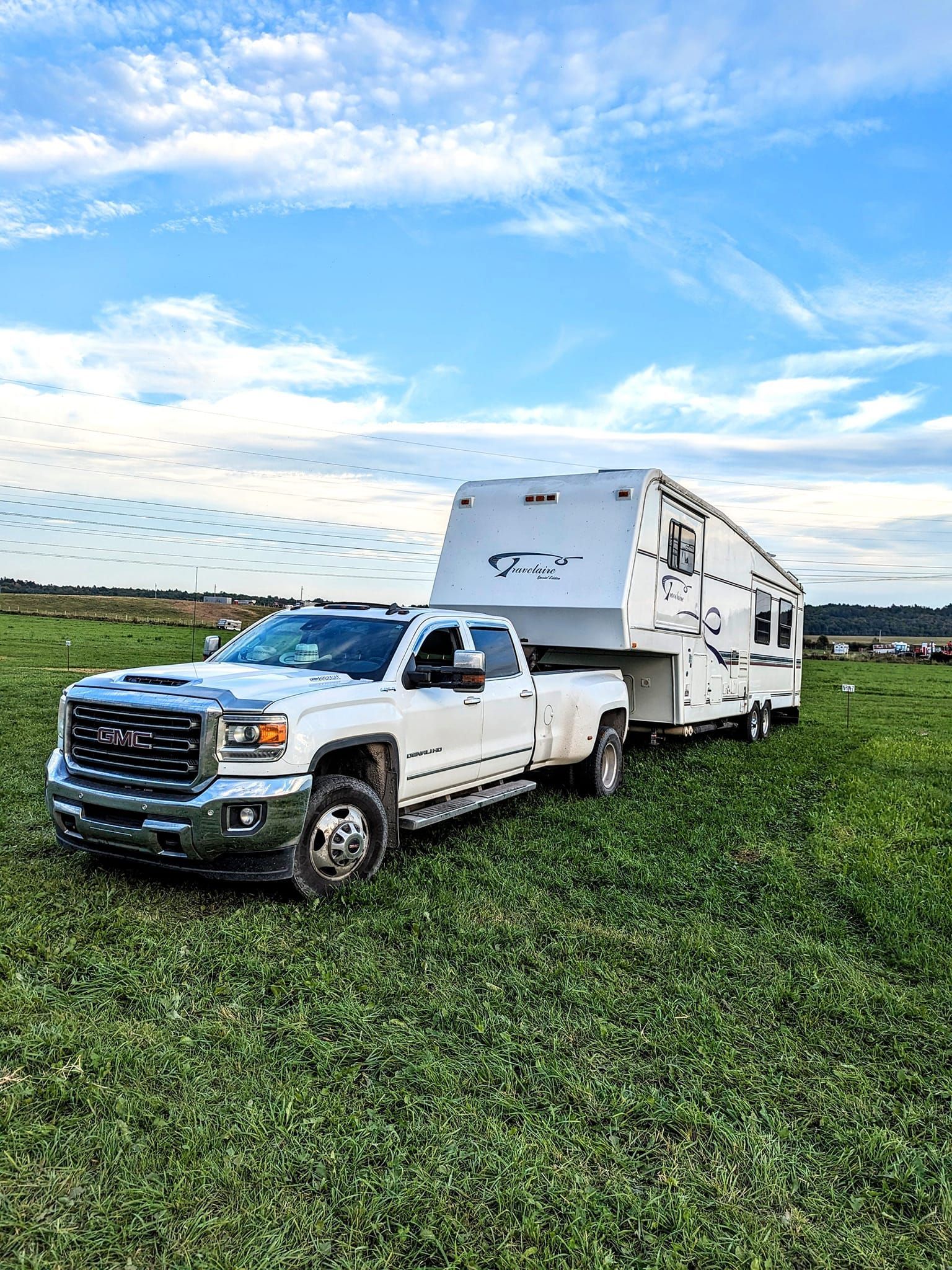 Un camion blanc tracte une remorque dans un champ herbeux.