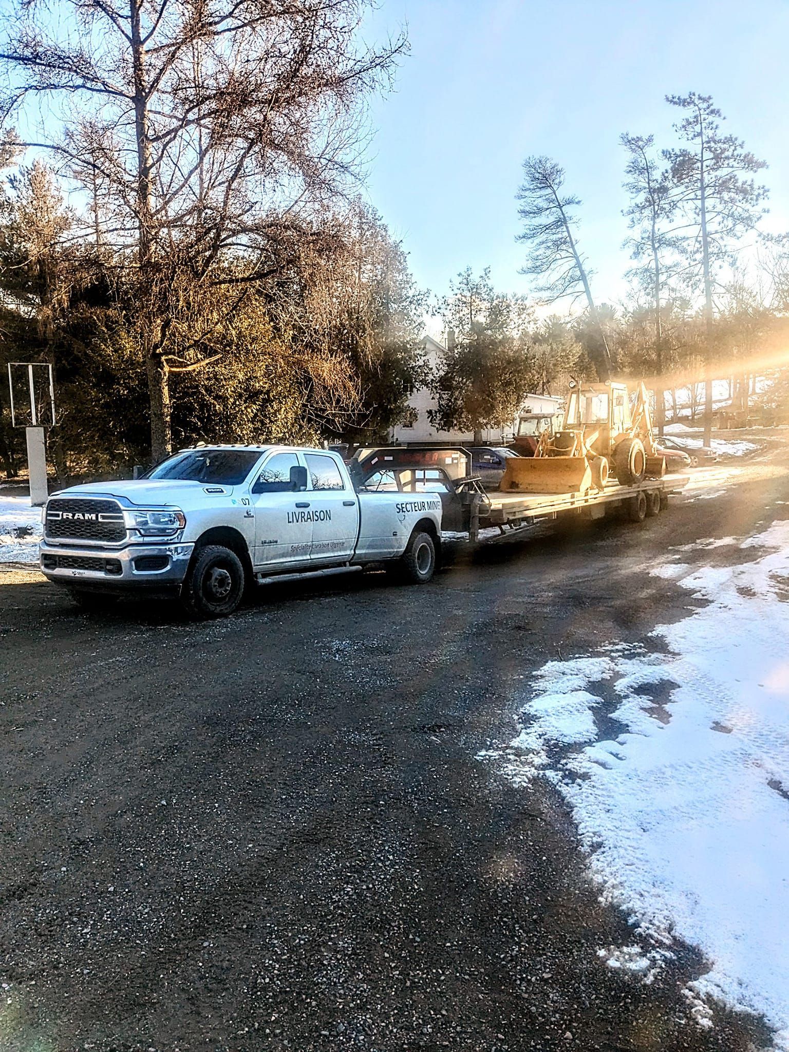 Un camion blanc tire une remorque sur une route enneigée.