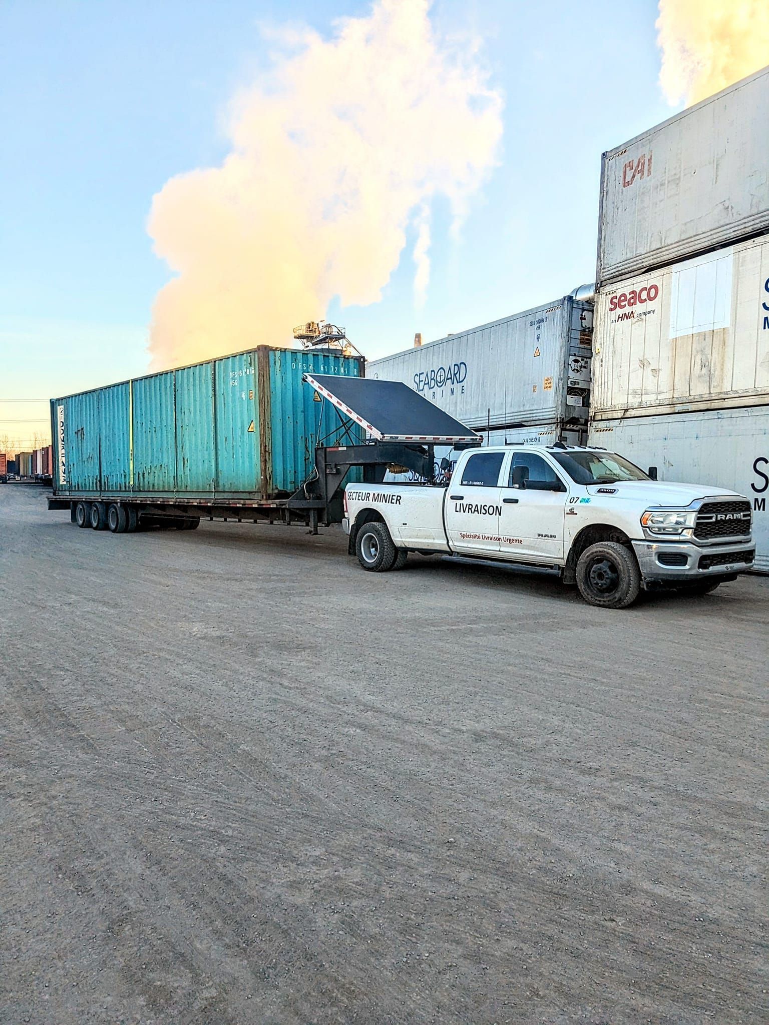 Un camion blanc remorque un conteneur d'expédition bleu sur une remorque.