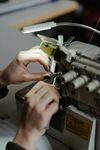 Handen die stof op een naaimachine rechtleggen onder een fel licht.