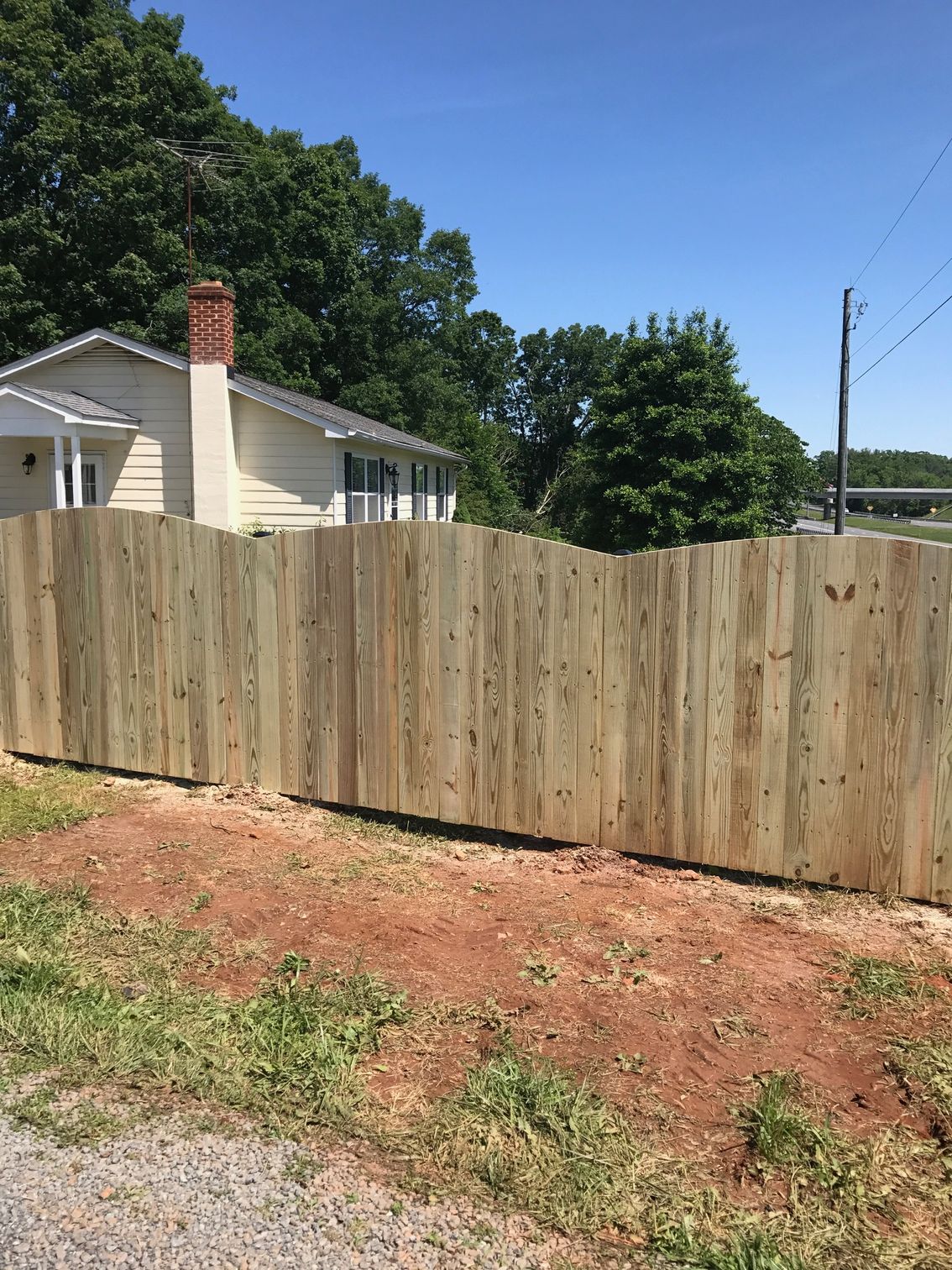 Wooden fence in front of a light-colored house on a sunny day.