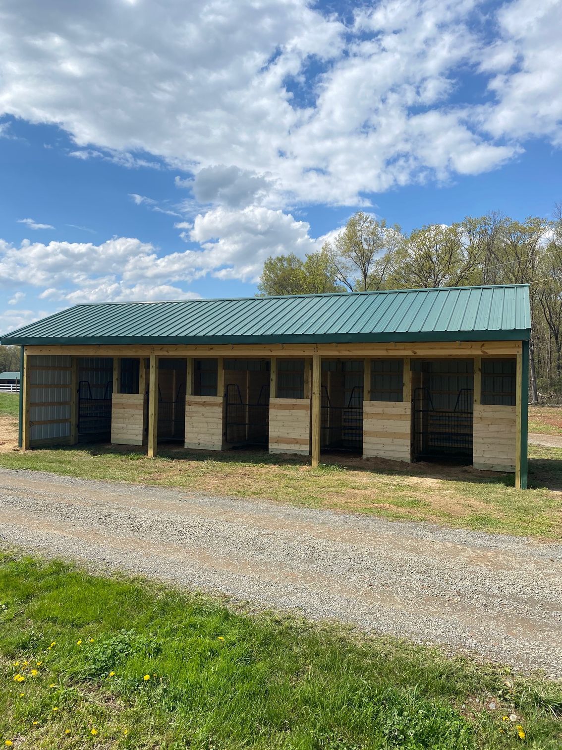 Horse stable with green roof and gravel drive.