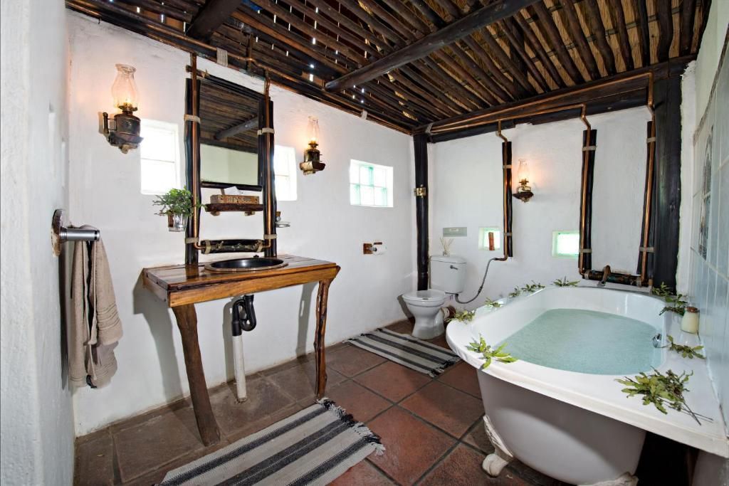 Rustic bathroom with clawfoot tub, wooden table, and bamboo ceiling.
