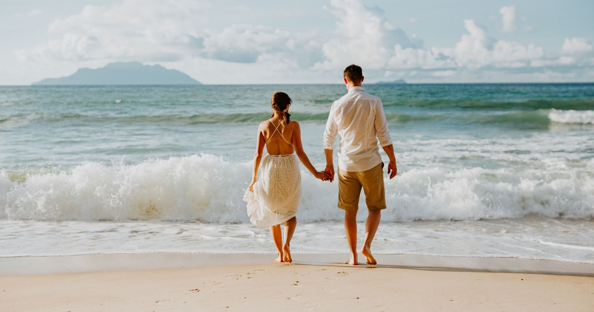 A man and a woman are walking on the beach holding hands. Seychelles