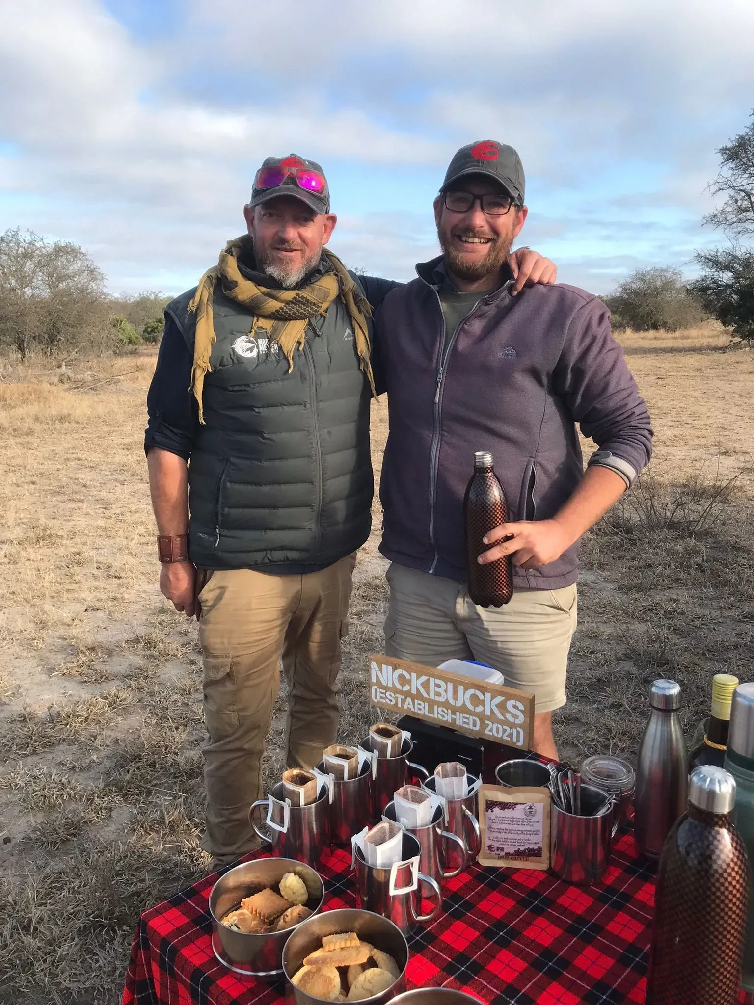 Two men are standing next to each other in front of a table.