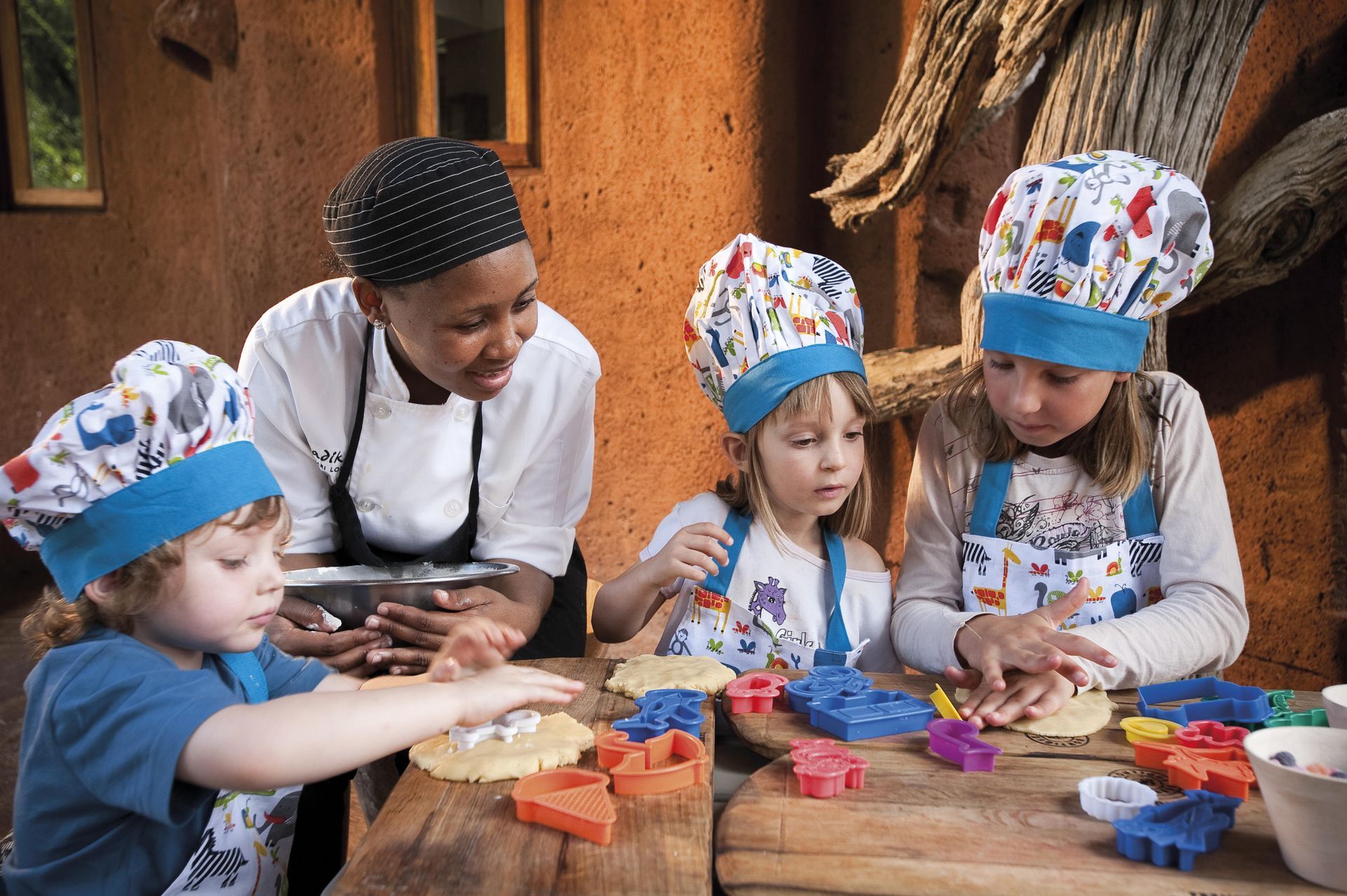 A group of children are sitting at a table wearing chef hats and aprons. Malaria Free Safari Destinations