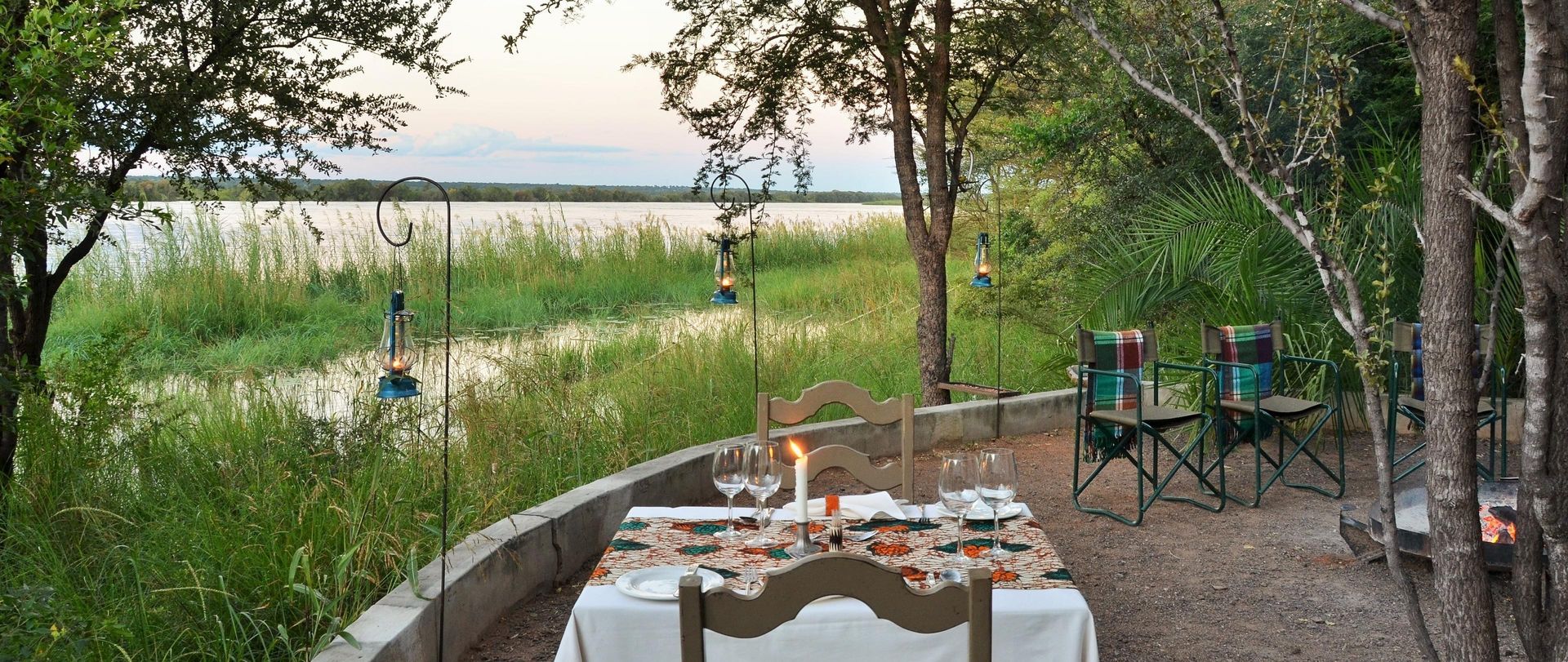 A table and chairs are set for a dinner in the woods.