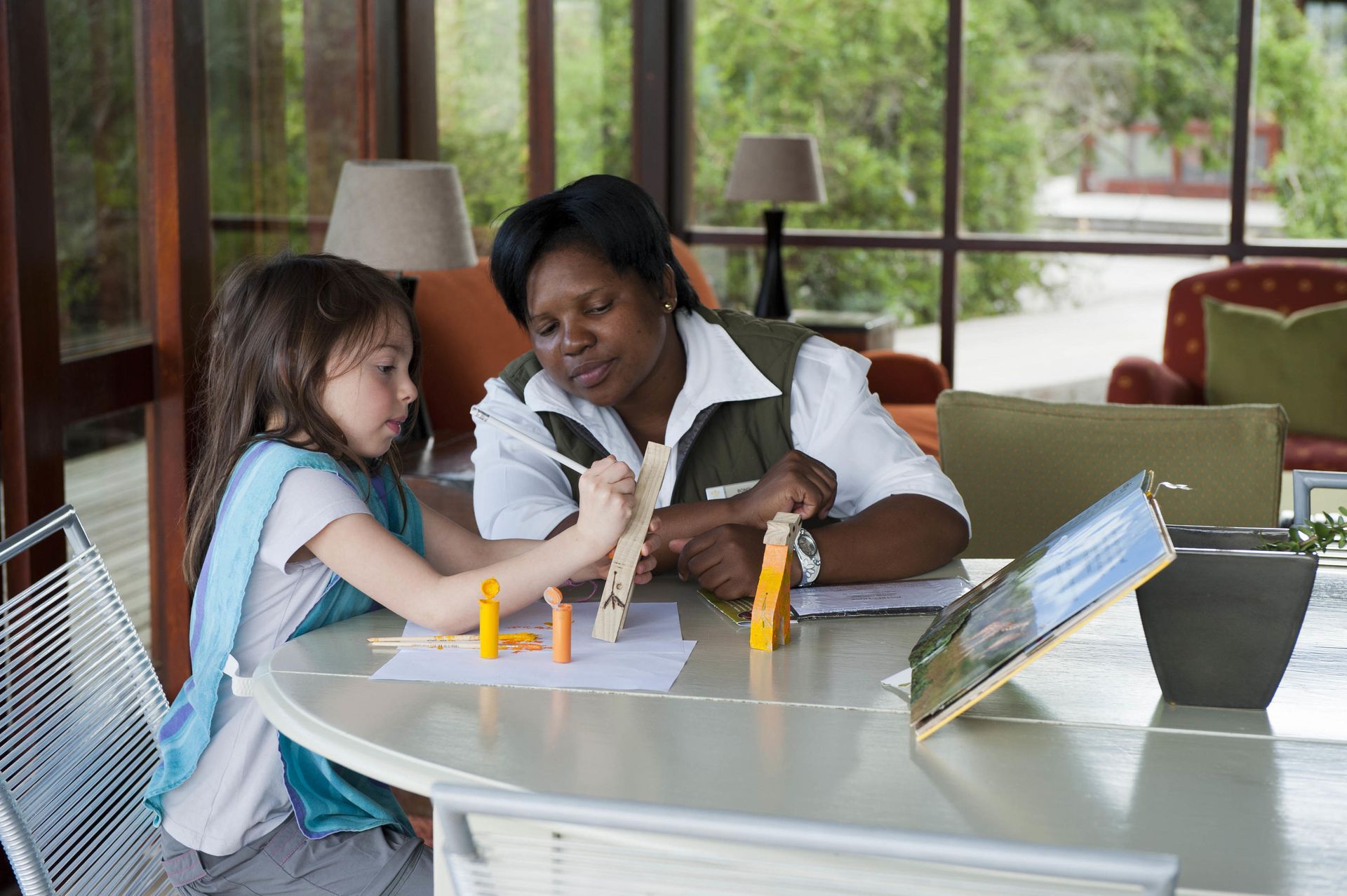A woman and a little girl are sitting at a table playing with toys. Malaria Free Safari Destinations