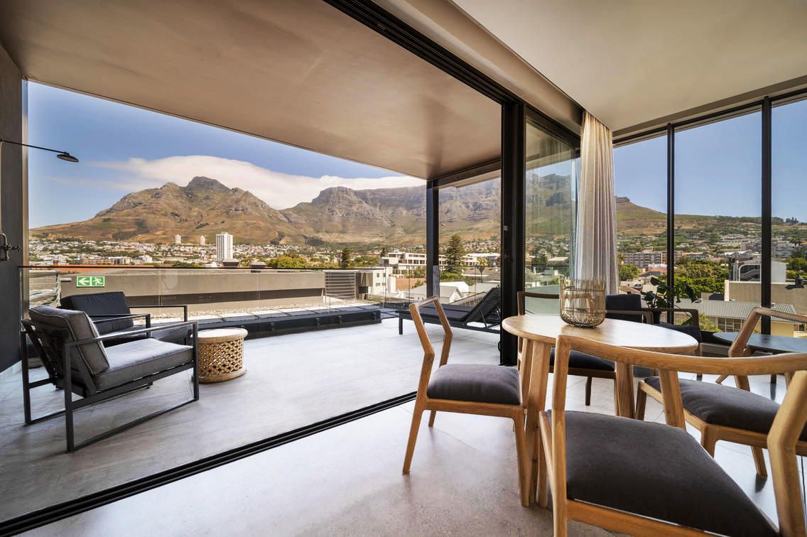 Balcony with mountain view, round table with chairs, lounge seating.