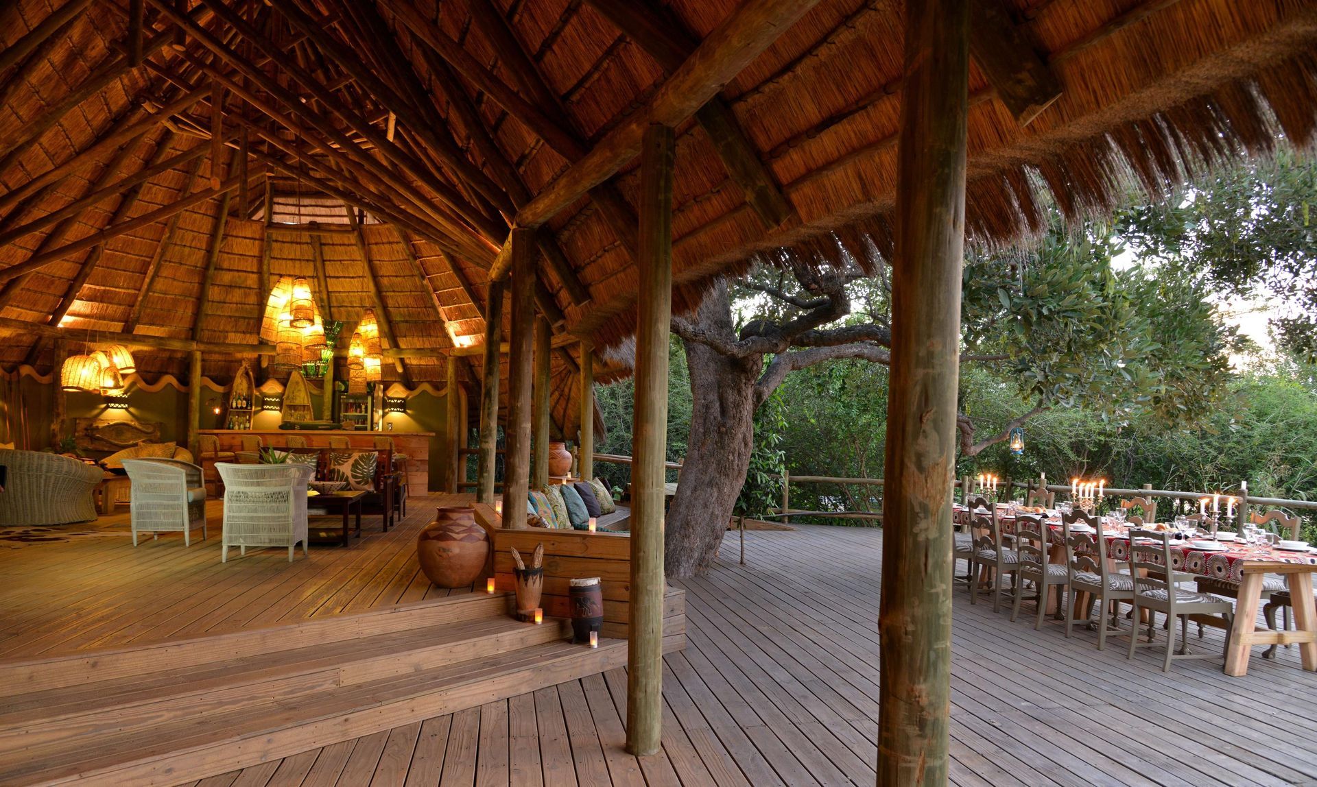 A large room with tables and chairs under a thatched roof