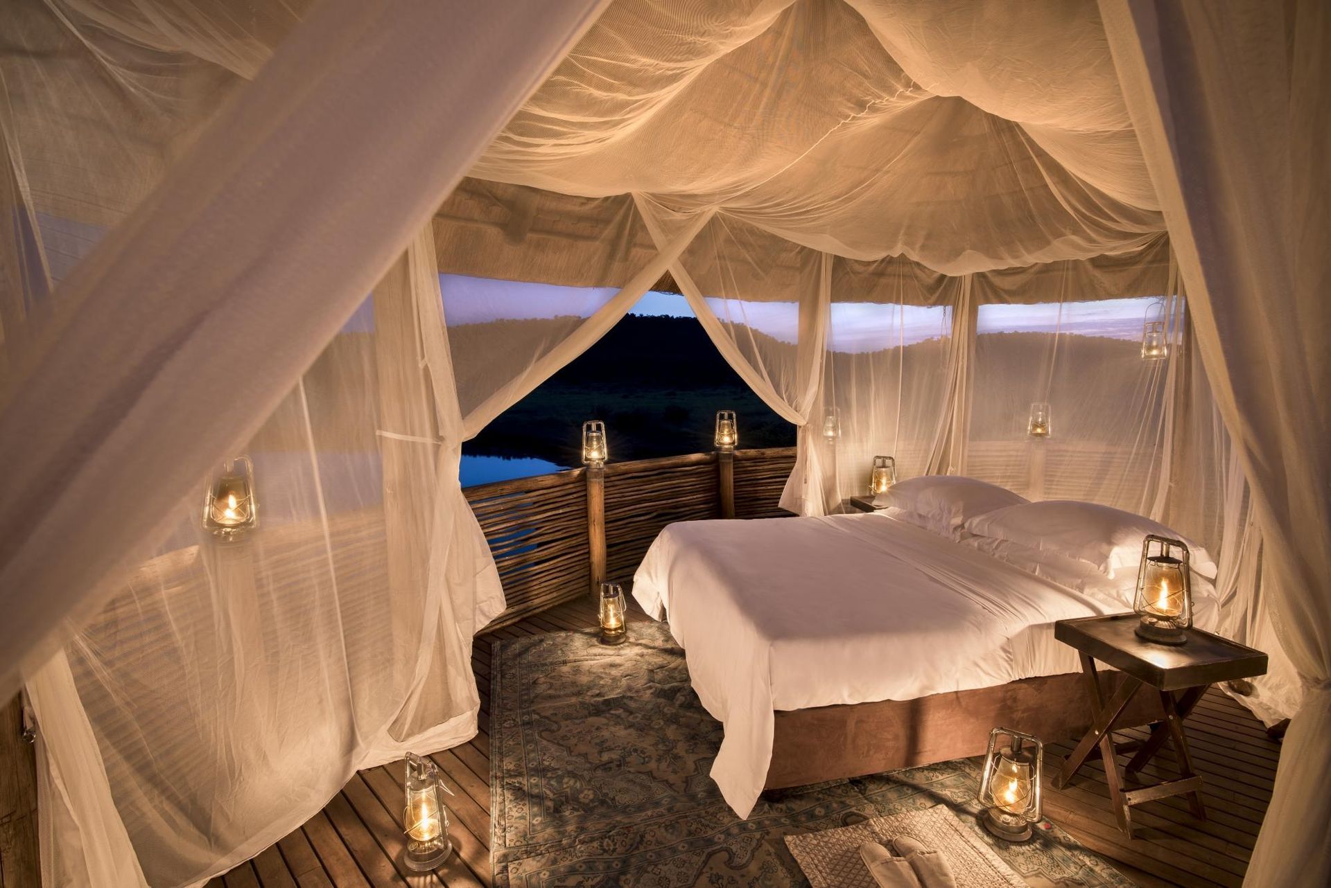 A tent with a bed and lanterns inside of it Malaria Free Safari Destinations
