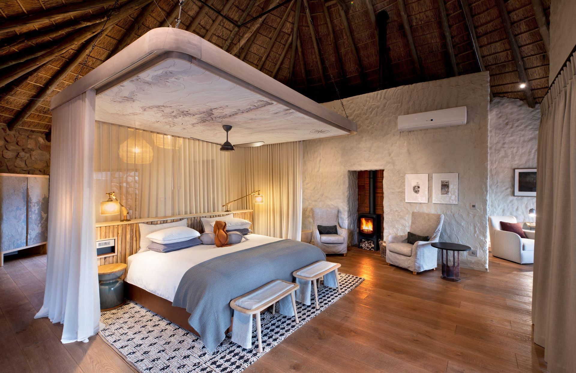 A bedroom with a canopy bed , chairs and a fireplace. Malaria Free Safari Destinations
