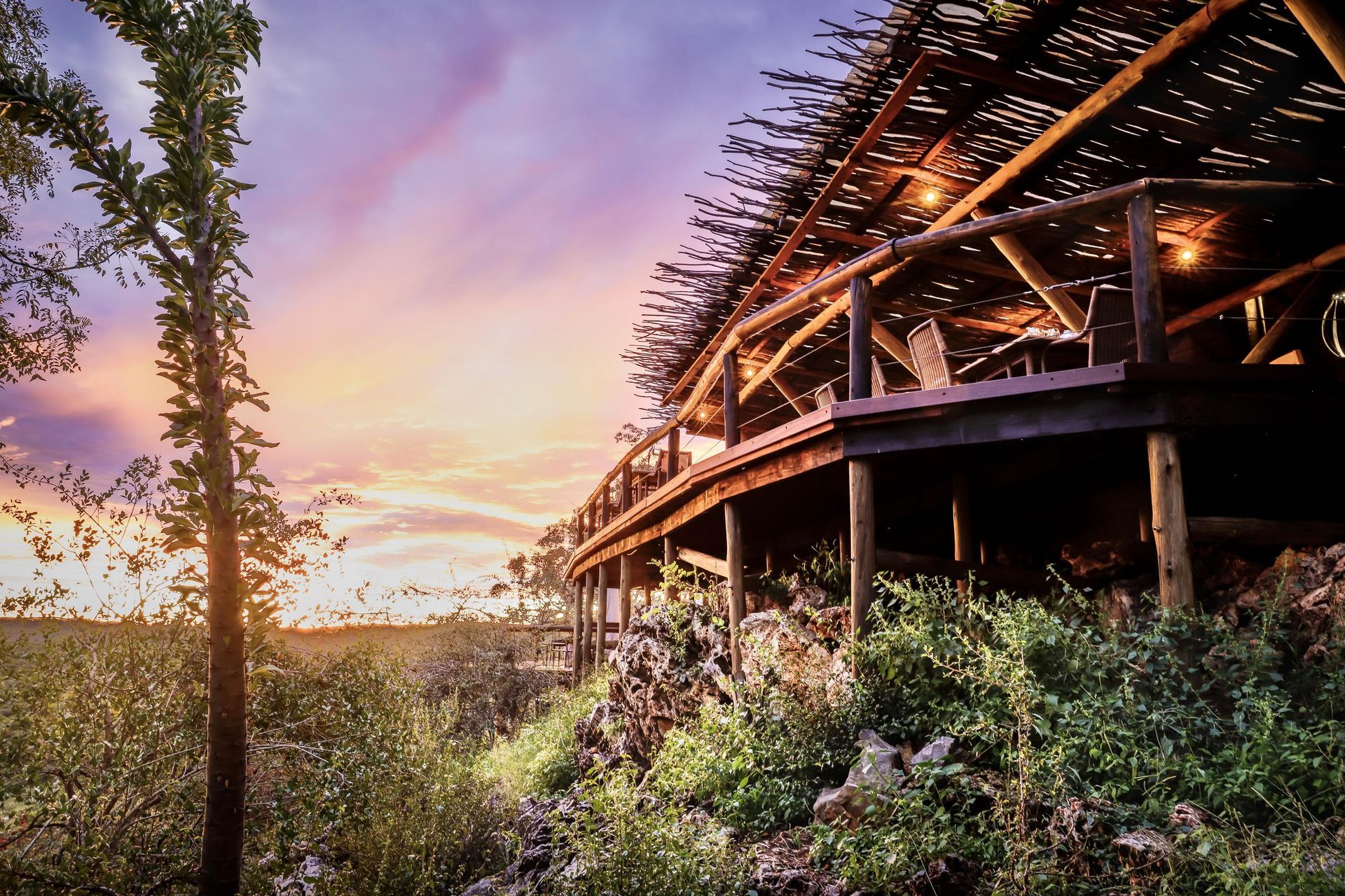 A wooden bridge over a river with a sunset in the background Luxury African Safaris Ongava Lodge