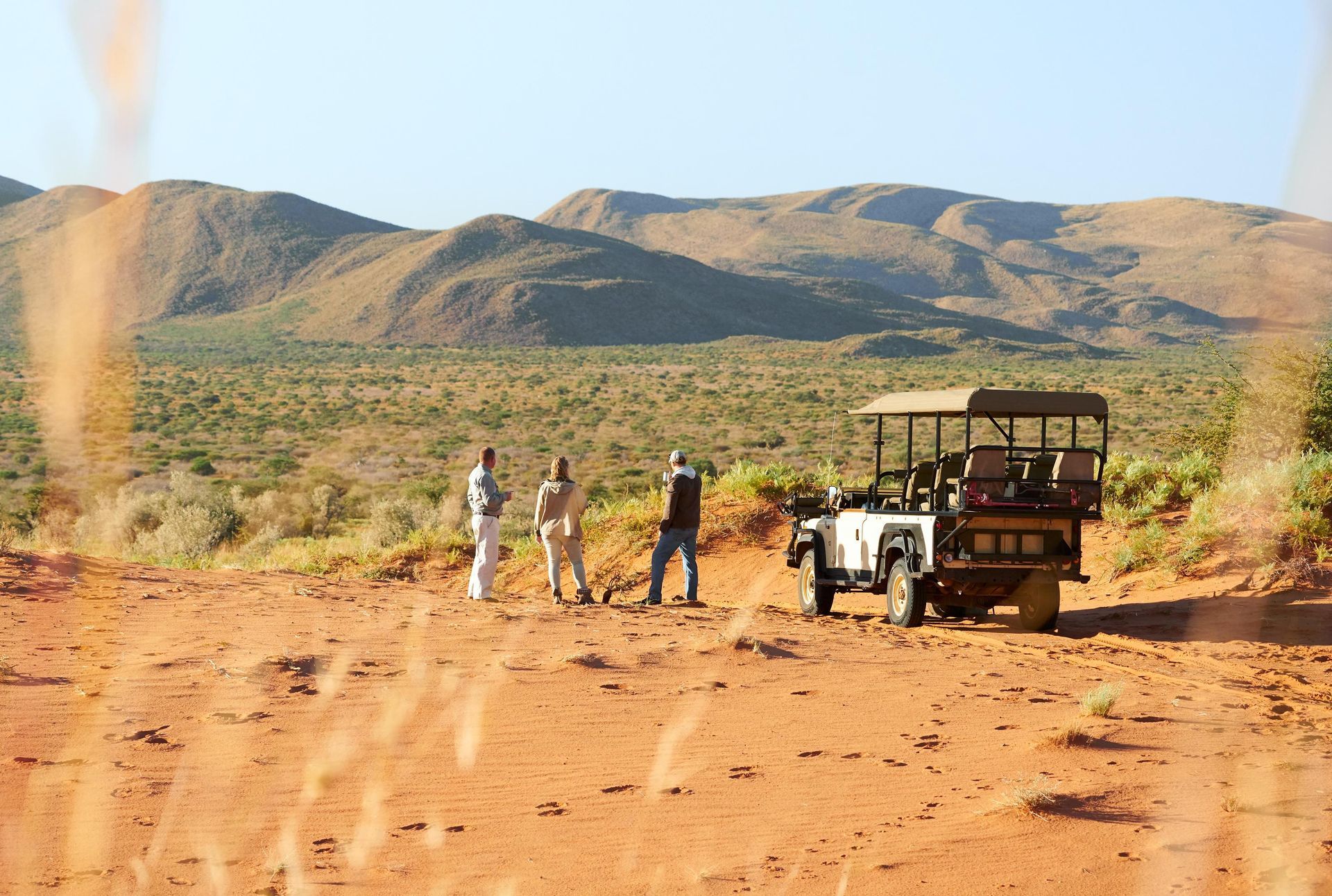 A group of people are standing next to a jeep in the desert. Malaria Free Safari Destinations
