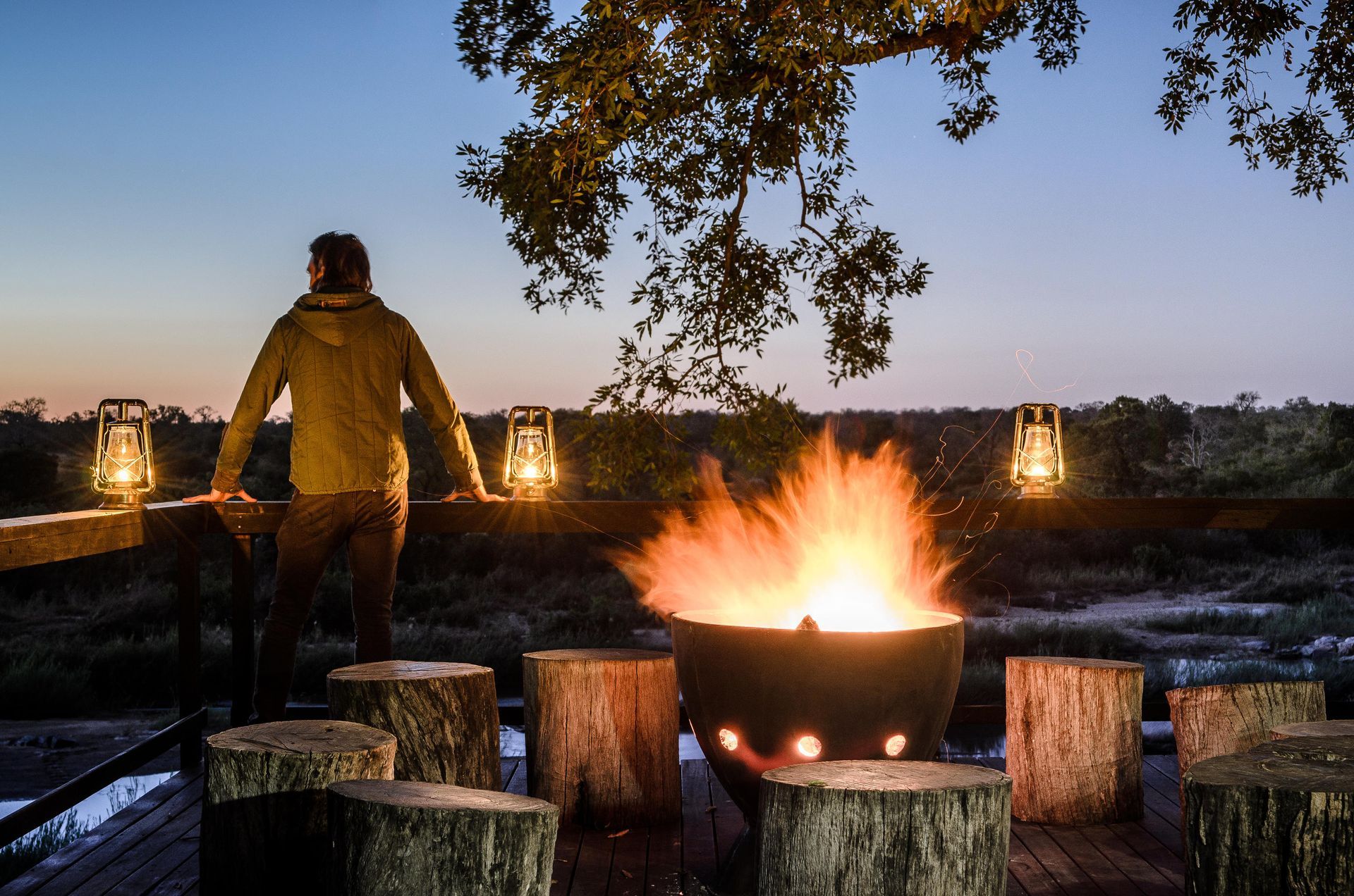 A man is standing on a deck overlooking a fire pit.Luxury African Safaris