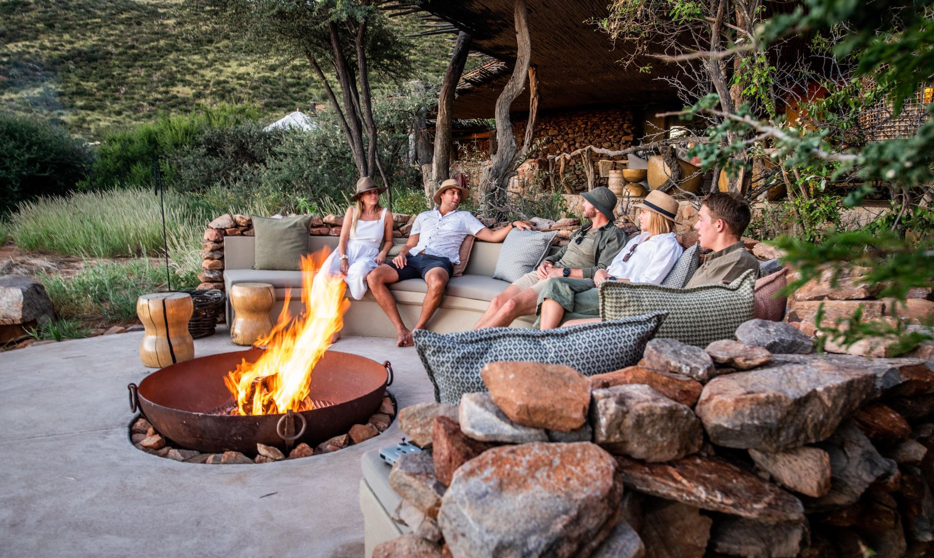 A group of people are sitting around a fire pit. Malaria Free Safari Destinations