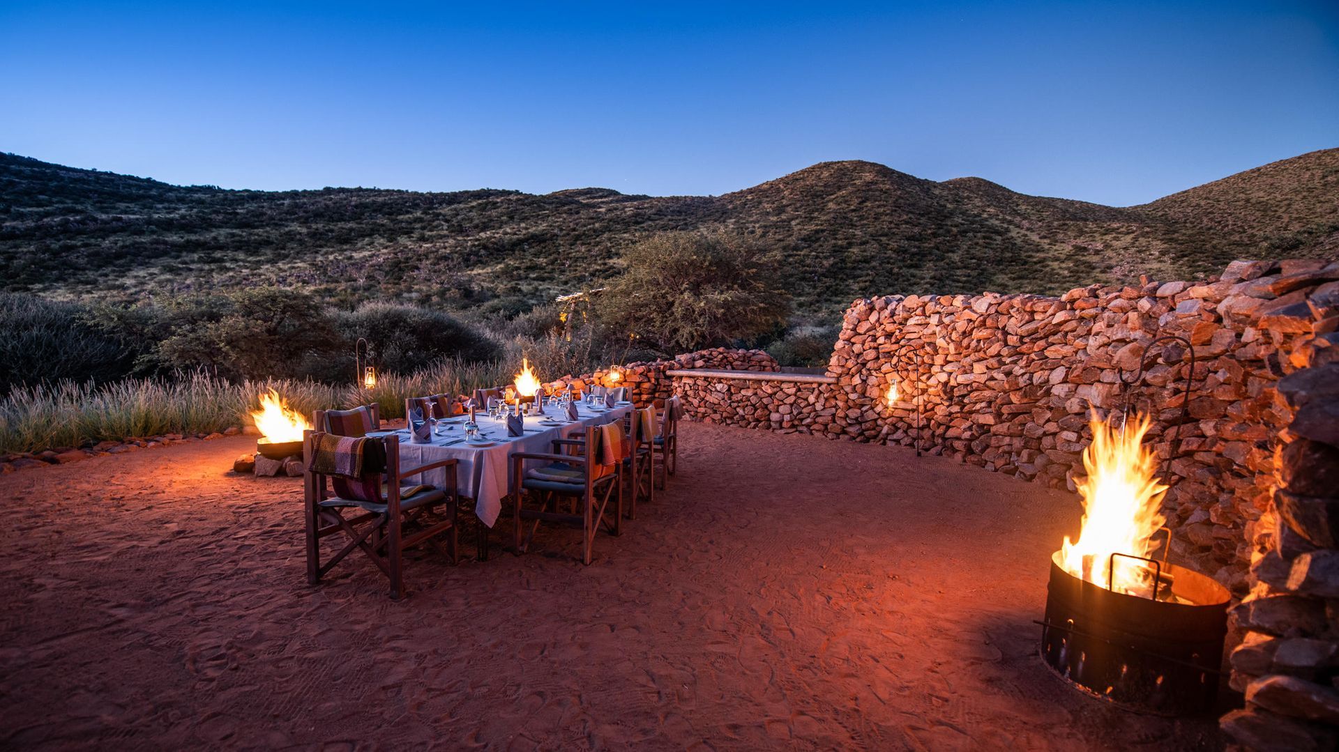 A long table and chairs are sitting in front of a fire pit. Malaria Free Safari Destinations