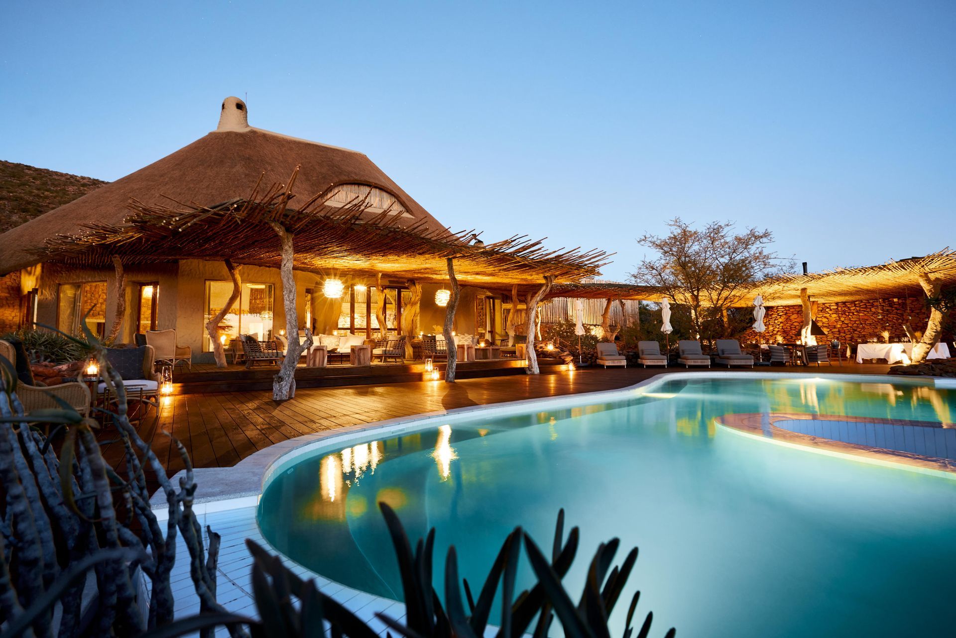 A large swimming pool in front of a thatched building Malaria Free Safari Destinations