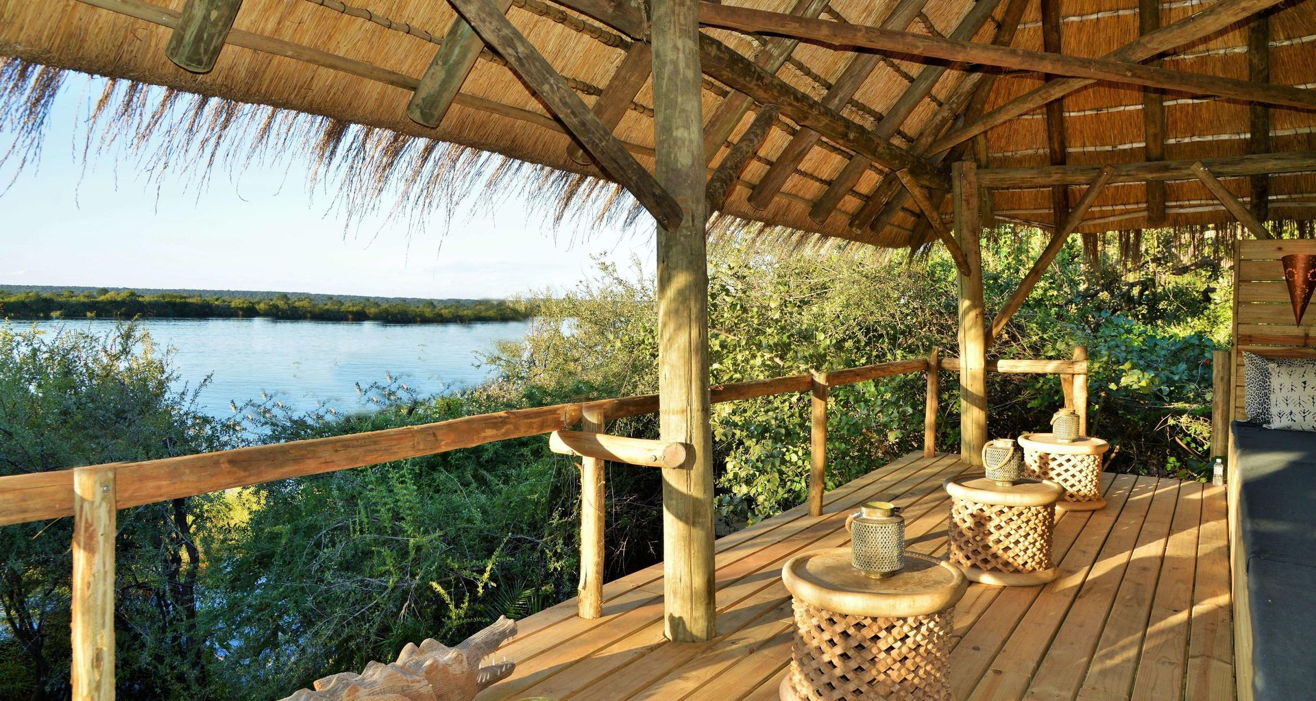 A wooden deck with a thatched roof overlooking a body of water.