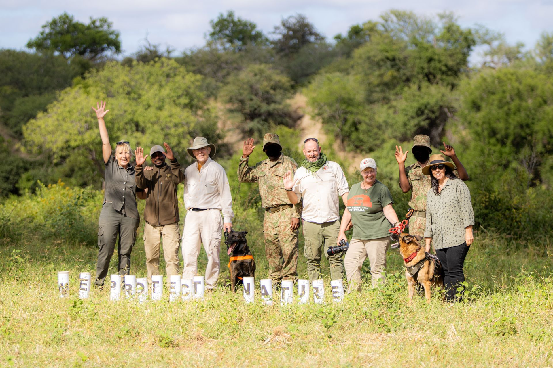 Group in a field with two dogs holding signs, 