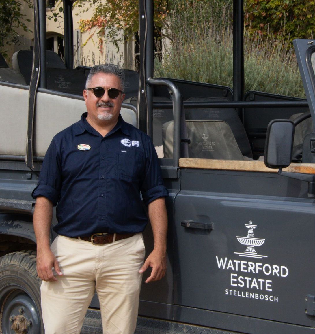A man stands in front of a waterford estate vehicle