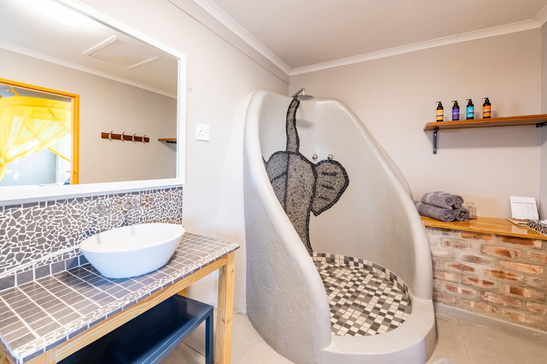Bathroom with a unique curved shower, mosaic details, and a vessel sink.
