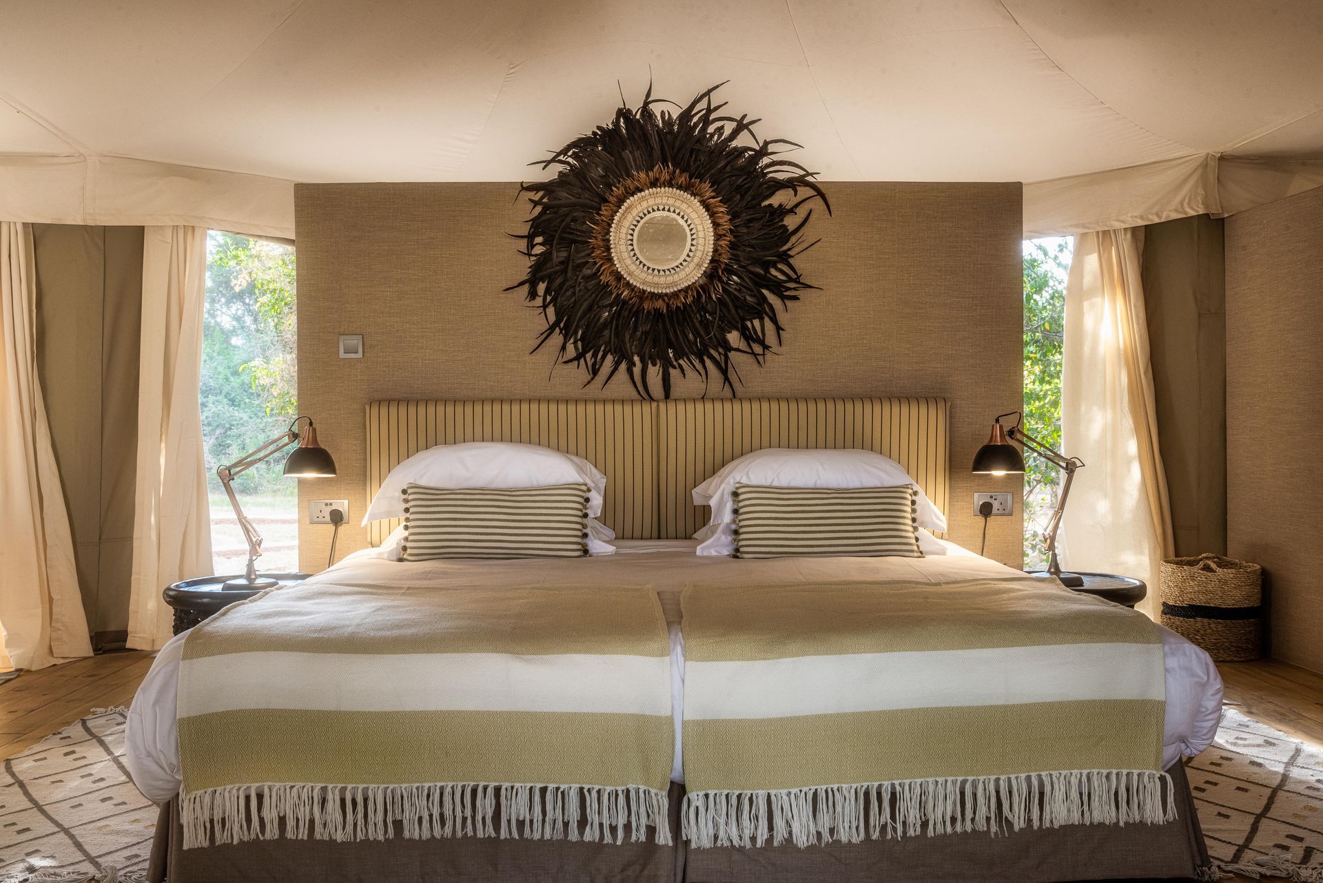 Luxurious safari bedroom with twin beds, decorative mirror, and side lamps.