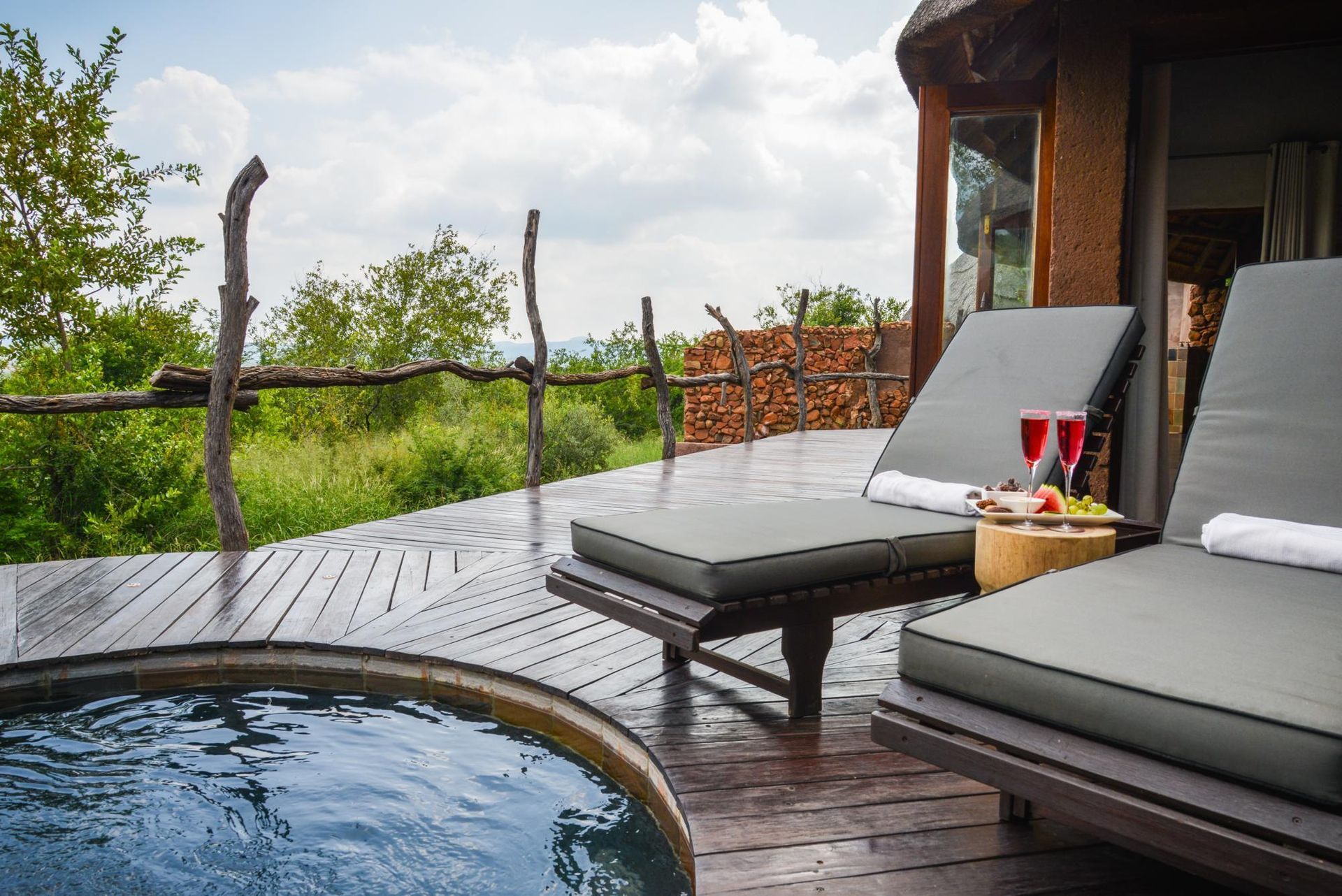 Two lounge chairs are sitting next to a swimming pool on a deck. Malaria Free Safari Destinations