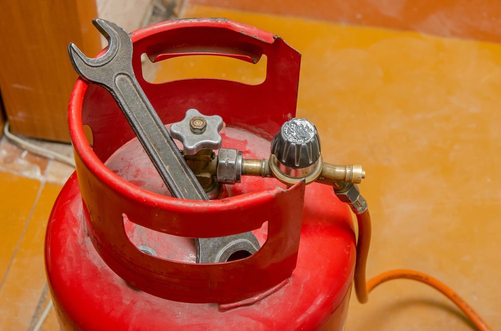 A Red Gas Cylinder With a Wrench in It — Todd Williams Plumbing and Gas Fitting In Nabiac, NSW