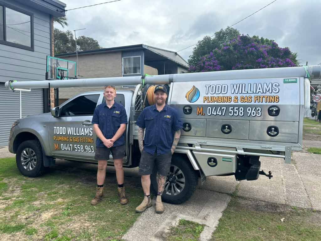 Two Men Are Standing In Front Of A Truck — Todd Williams Plumbing and Gas Fitting In Forster, NSW