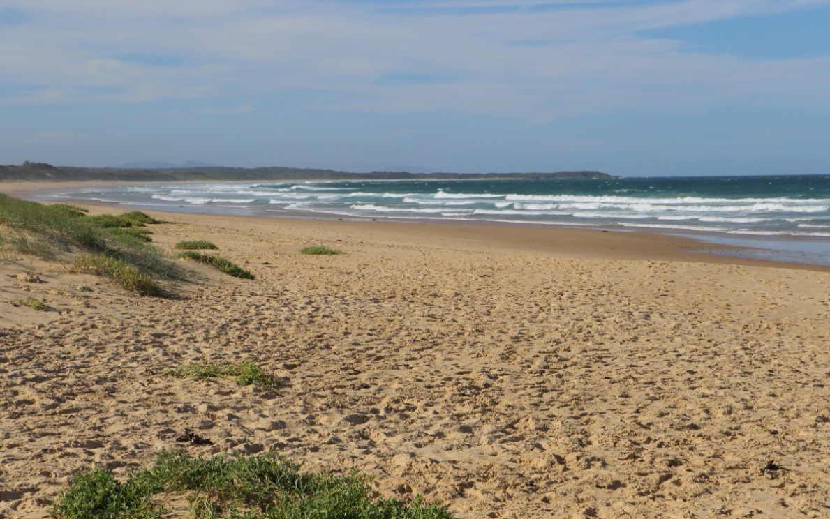 A Sandy Beach With Waves Crashing on the Shore on a Sunny Day — Todd Williams Plumbing and Gas Fitting In Diamond Beach, NSW