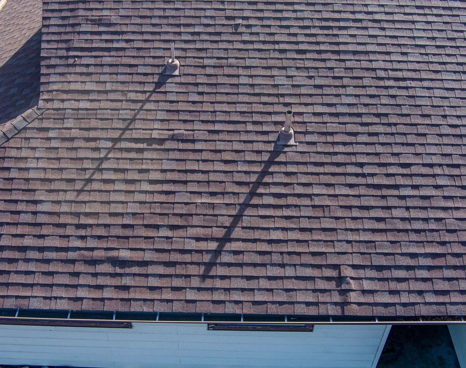 Roof with brown shingles and two dark diagonal shadows