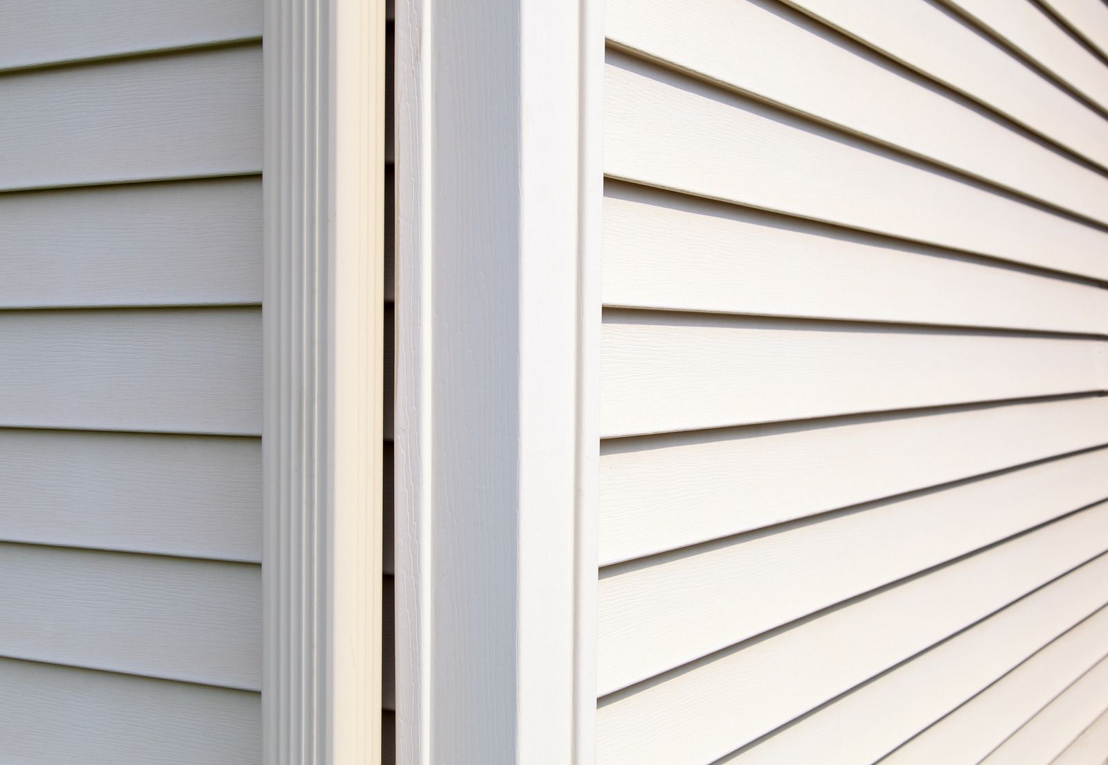 Close-up of white and gray house siding along an exterior corner trim.