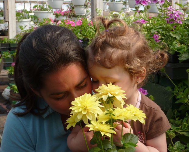 Une femme et un enfant sentent des fleurs jaunes dans une serre.