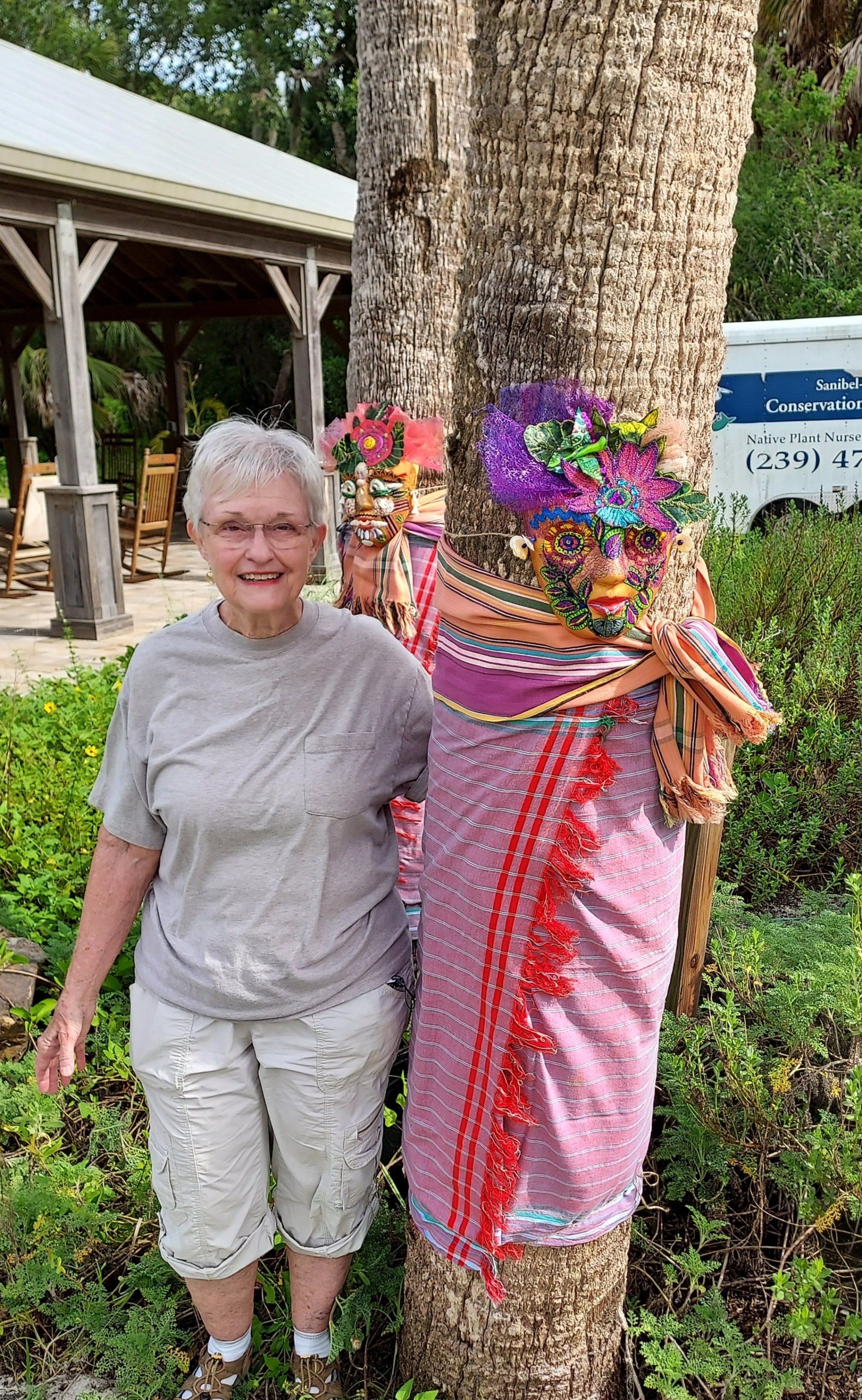 Woman stands by decorated trees with colorful fabric and floral accents.