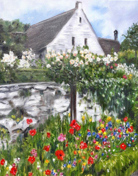 Cottage with white walls, thatched roof, and colorful garden, with a stone wall in the foreground.