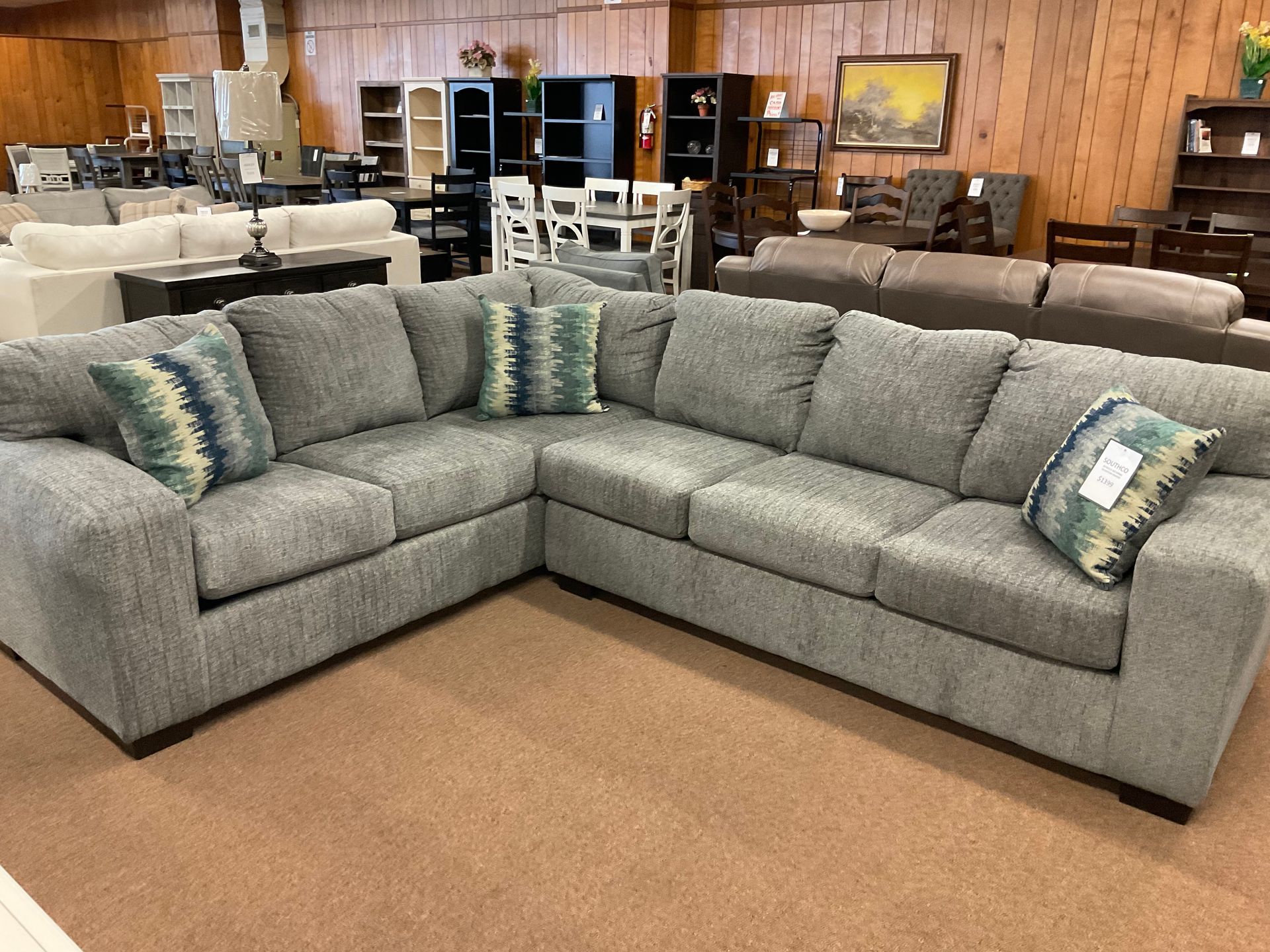 Gray sectional sofa with patterned throw pillows in a furniture store.