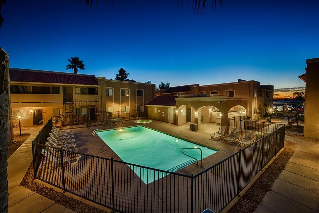 Courtyard apartment complex with a lit turquoise swimming pool at dusk