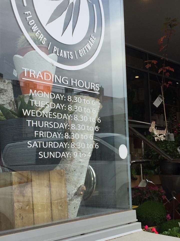 A window with a sign that says trading hours on it
