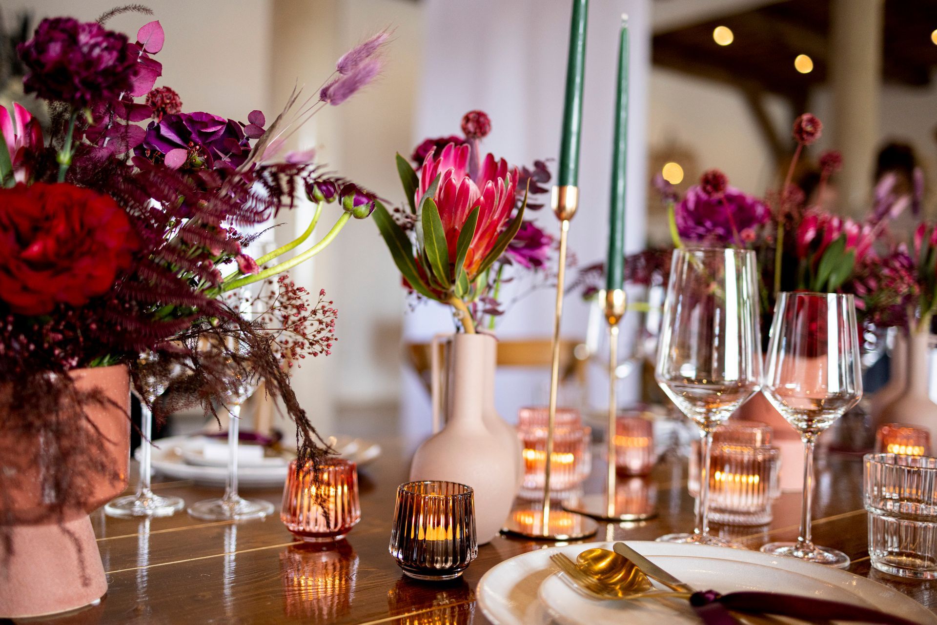 Elegant table setting with floral arrangement, candles, and glassware; a wedding reception.