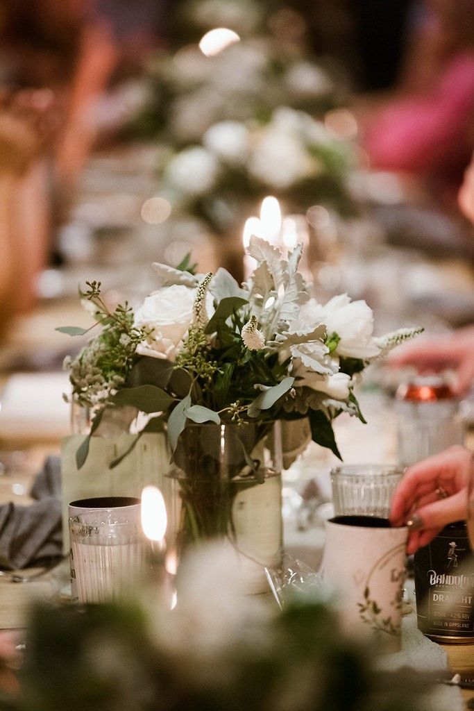 A table with a vase of flowers and a candle on it.