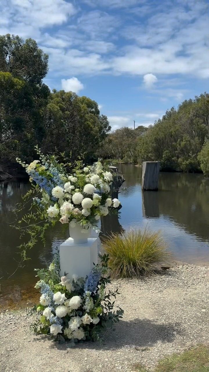 A bride in a white dress is standing in front of a tree.