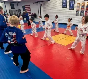 Martial arts class practicing stances on red and blue mats in a dojo
