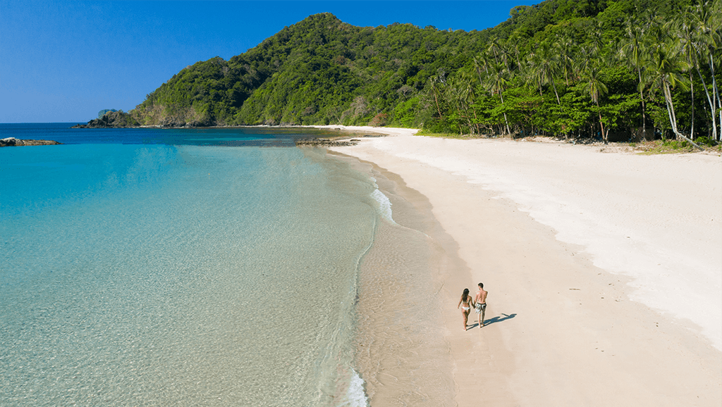 An aerial view of a couple walking on a beach.