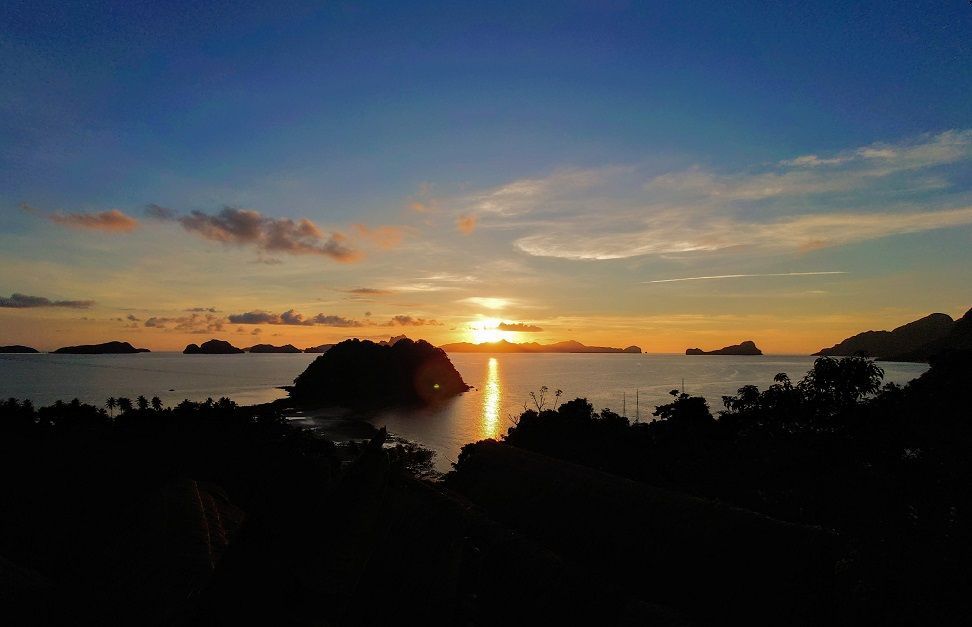 A sunset over a body of water with a few islands in the distance.