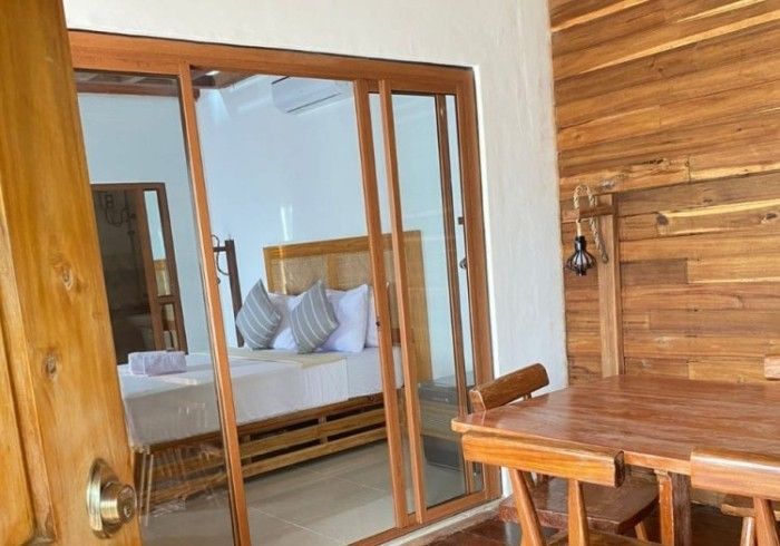 A bedroom with a table and chairs and a sliding glass door leading to a balcony.